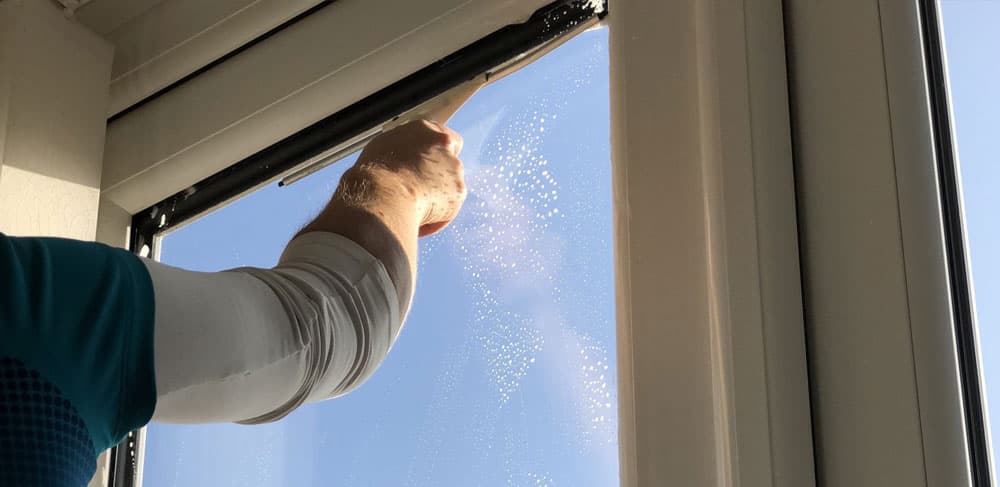 Professional window cleaner at work on a bright home